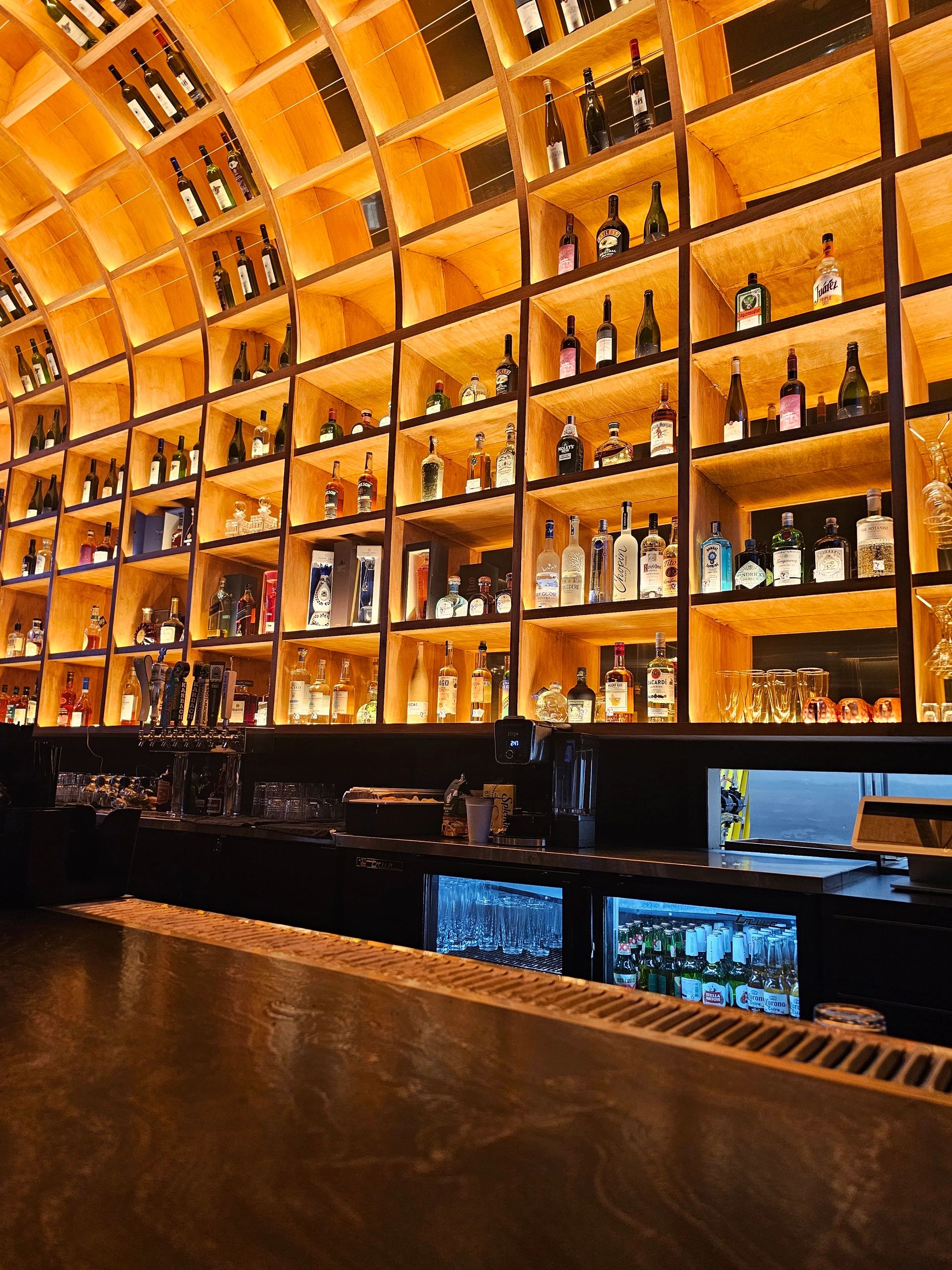 The bar at Cheroots, backlit bottles on cedar shelving