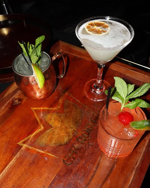Three cocktails on a Cheroots-branded wooden serving tray